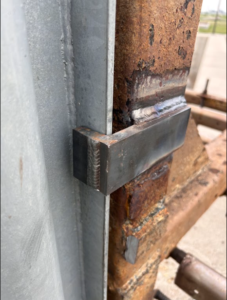 New steel bracket welded to the galvanised guide rail, joining clean prepped steel to weathered plant structure.