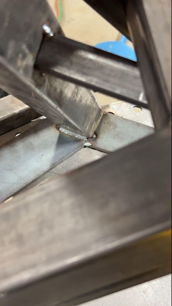 Close-up of a welded gusset where an angled brace meets the base of a steel frame.