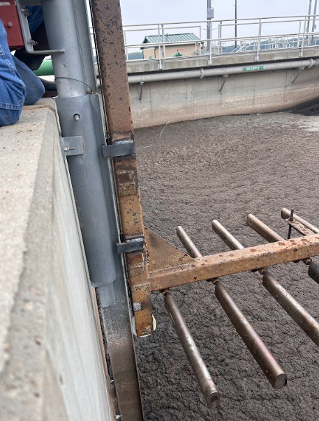 Bar screen rake arm and tine assembly repaired in place above the channel at a waste water treatment plant.