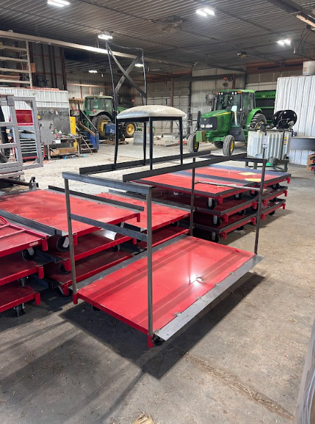 Steel racks fabricated to hold painted panels clear of the floor in a working shop.